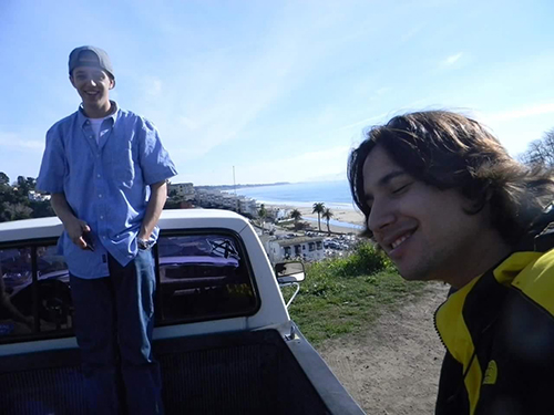 A picture of my friend and I, at the beach. We are in the back of a pickup truck on a cliff, overlooking the ocean.